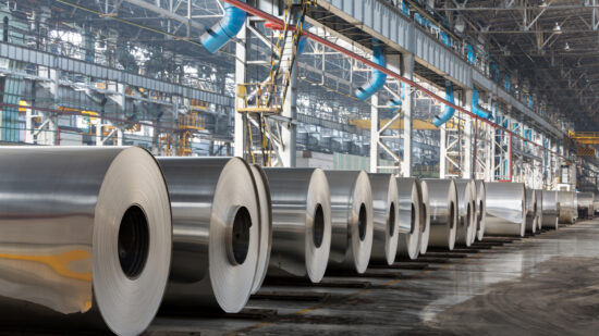 Row of rolls of aluminum lie in production shop of plant.