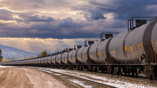 tanker cars of a freight train close to Whitefish, Montana under a beautiful cloudy sky