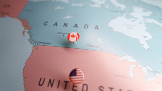 Canadian flag push pin marking Canada on a map